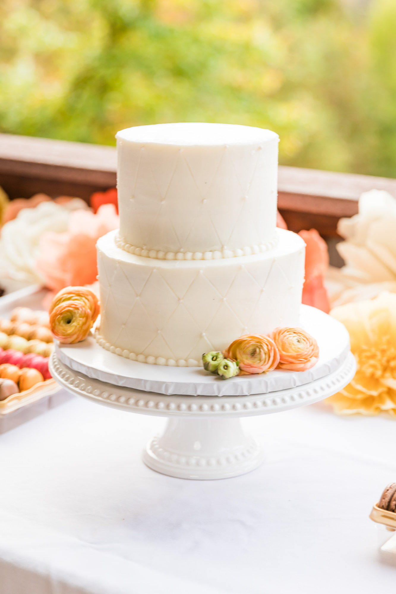 simple white two tier wedding cake with peach colored floral accents