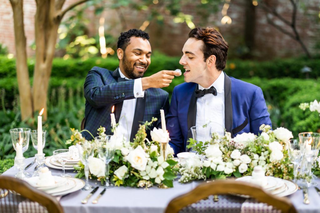 grooms feeding one another cake