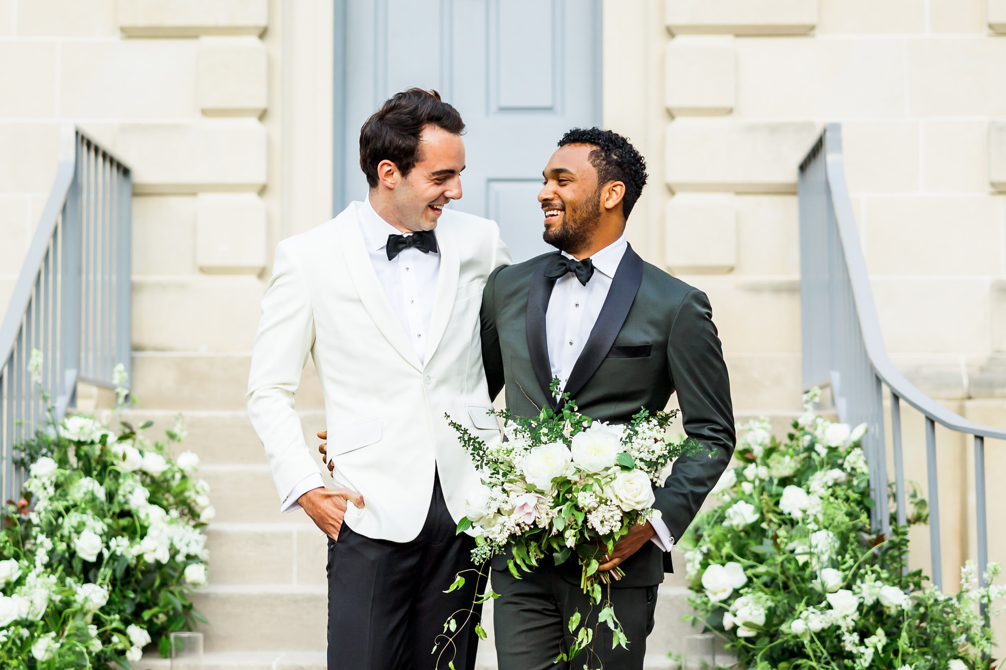 man wearing white tux, and another man wearing blue plaid jacket posing during bridals at bridgerton spring wedding inspiration