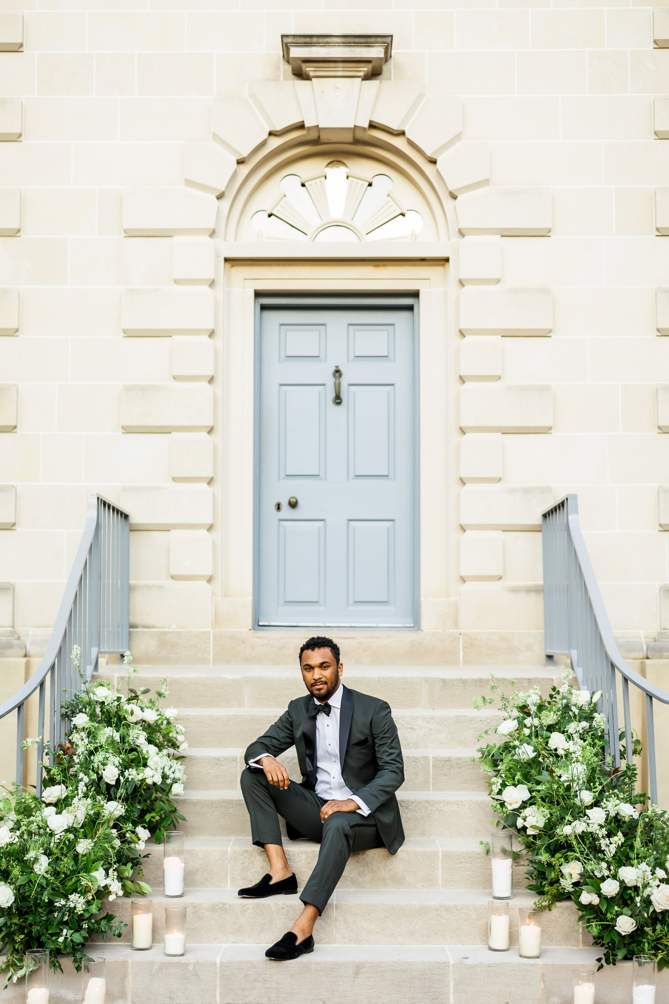 groom wearing olive tuxedo sitting on steps after Bridgerton inspired wedding