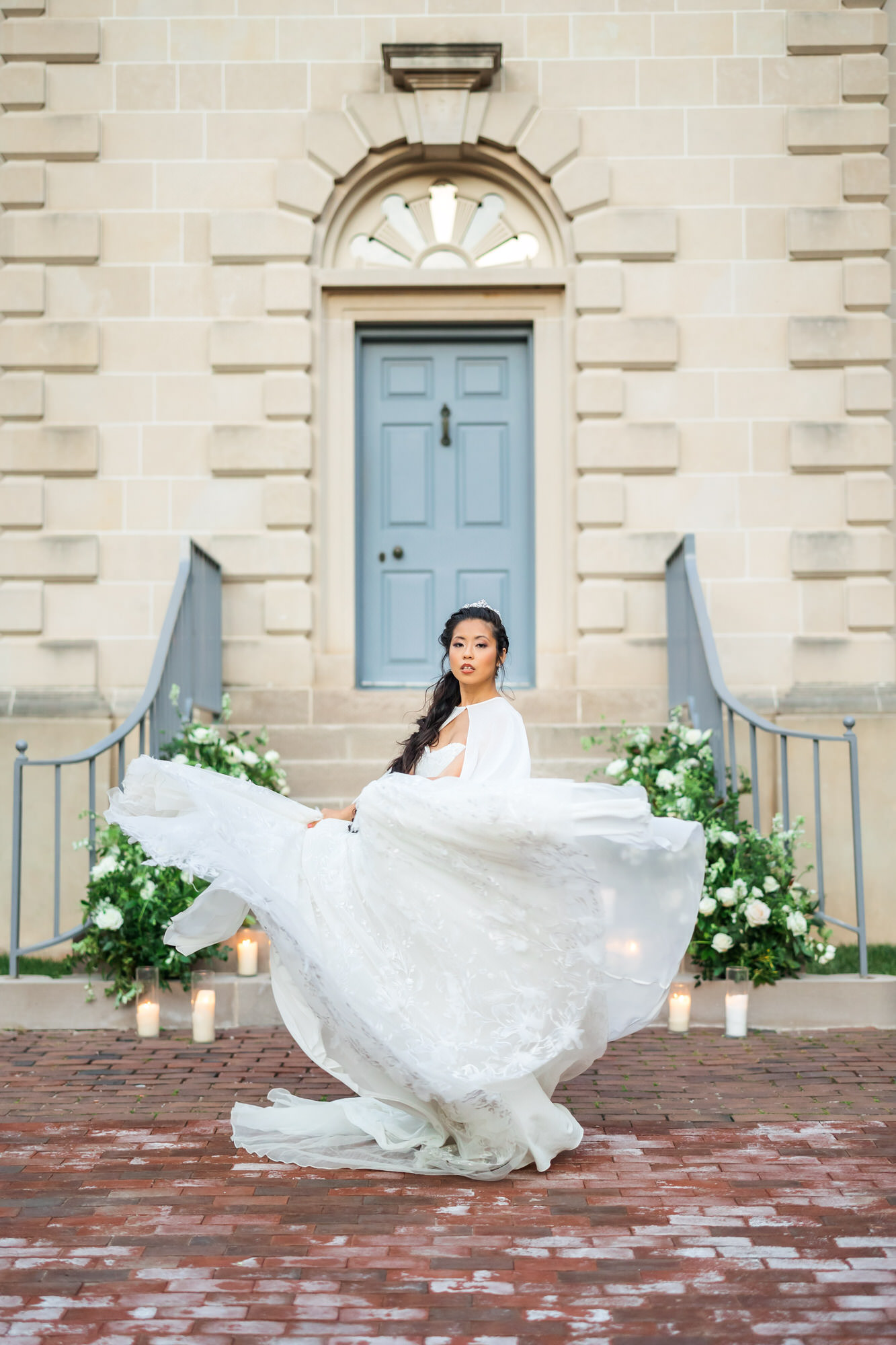 bride wearing cape and bridal gown swinging gown around in front of stairs at bridgerton spring wedding inspiration