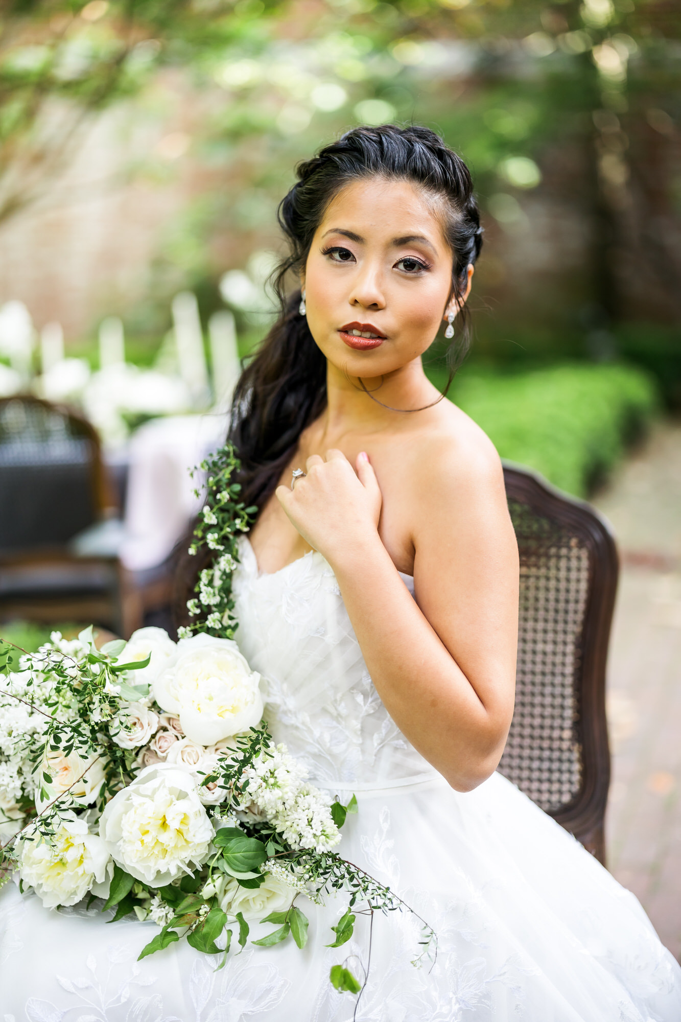 bride sitting at reception table with white and green bouquet 