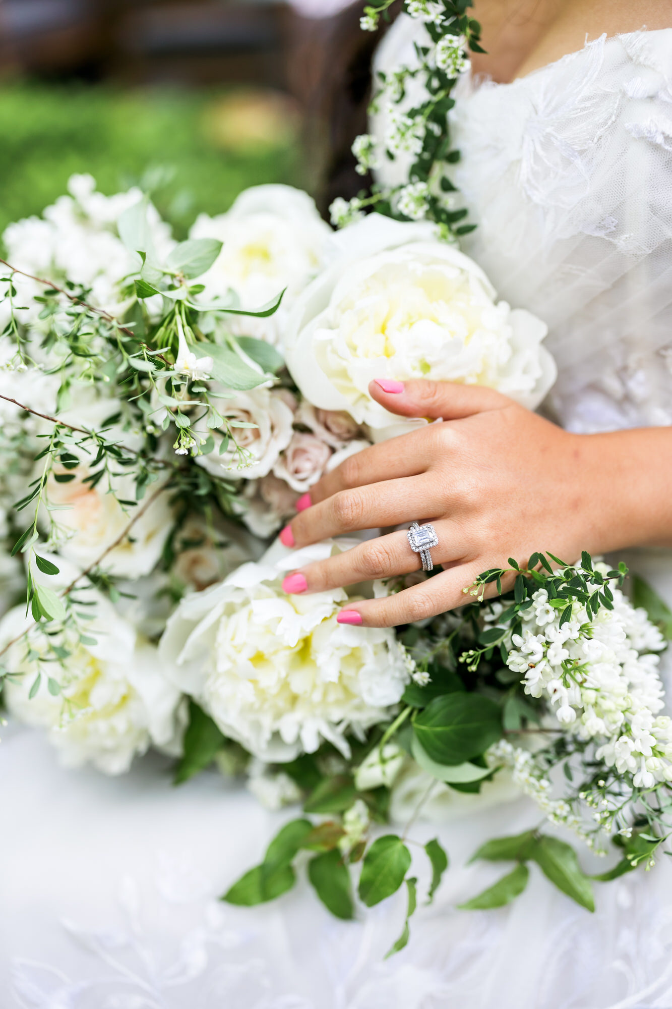 bride holding white flower and greenery filled bridal bouquet showing off wedding ring during detail shots