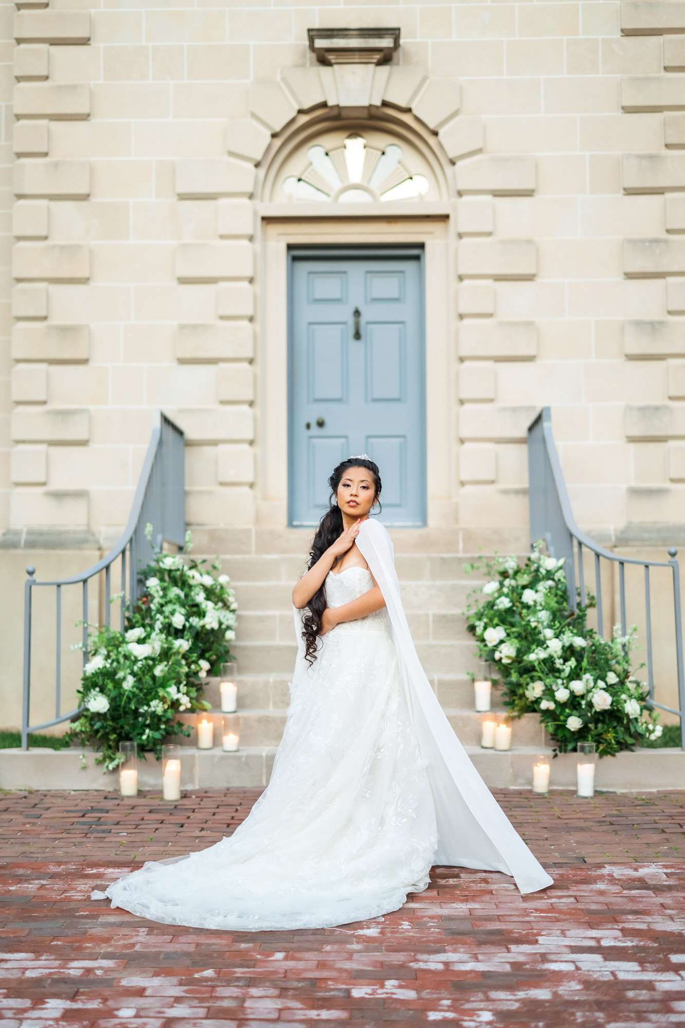 bride with hand on shoulder wearing strapless bridal gown and bridal cape