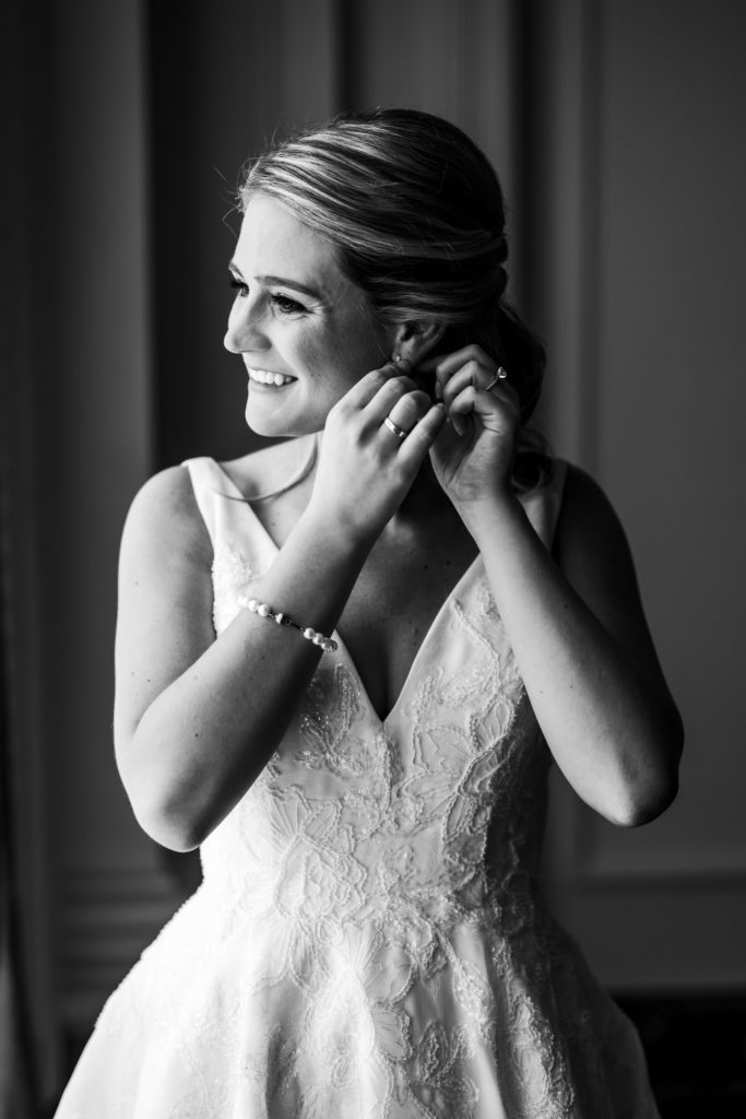 bride putting on earrings while getting ready for elegant jefferson hotel wedding