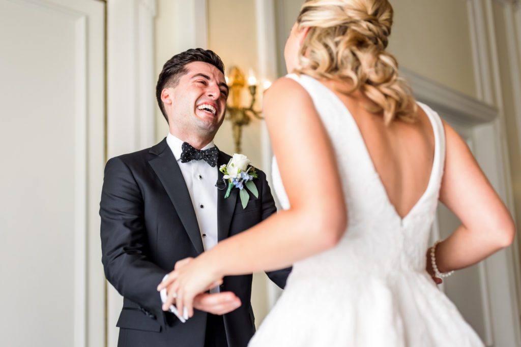 bride and groom laughing while seeing one another for first time on wedding day