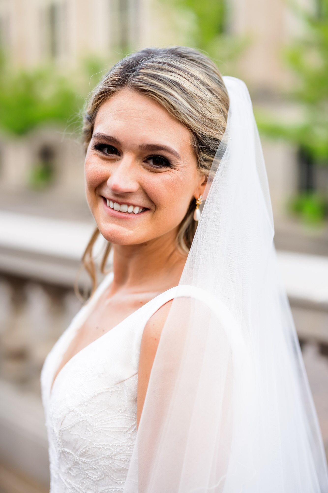 blonde woman in bridal gown and veil smiling at camera