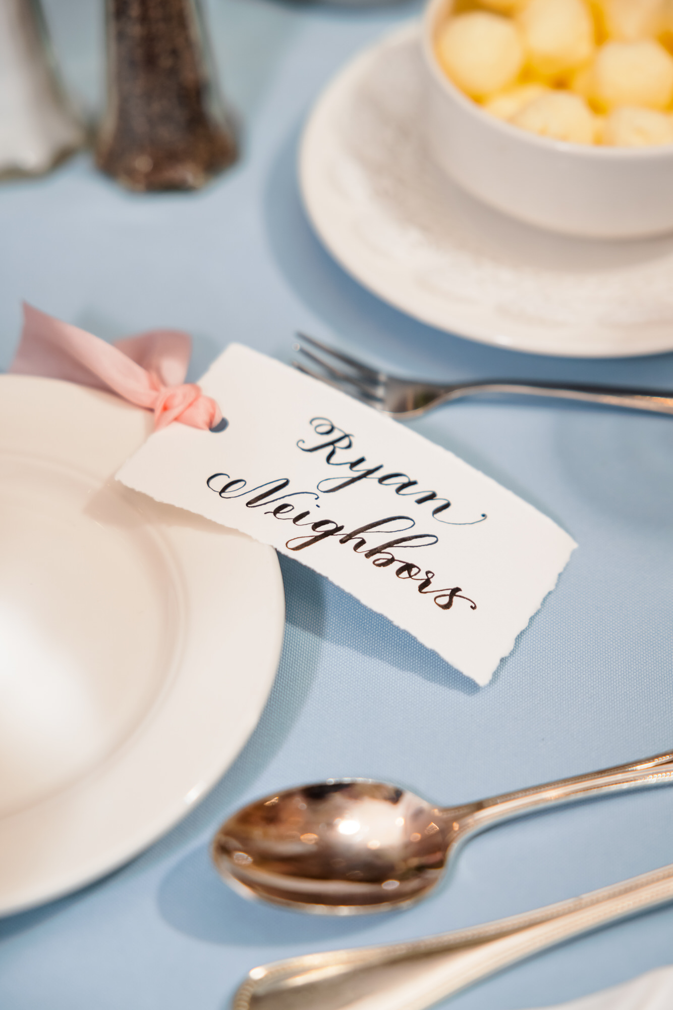 white handwritten name tags sitting on blue table cloth for elegant wedding day