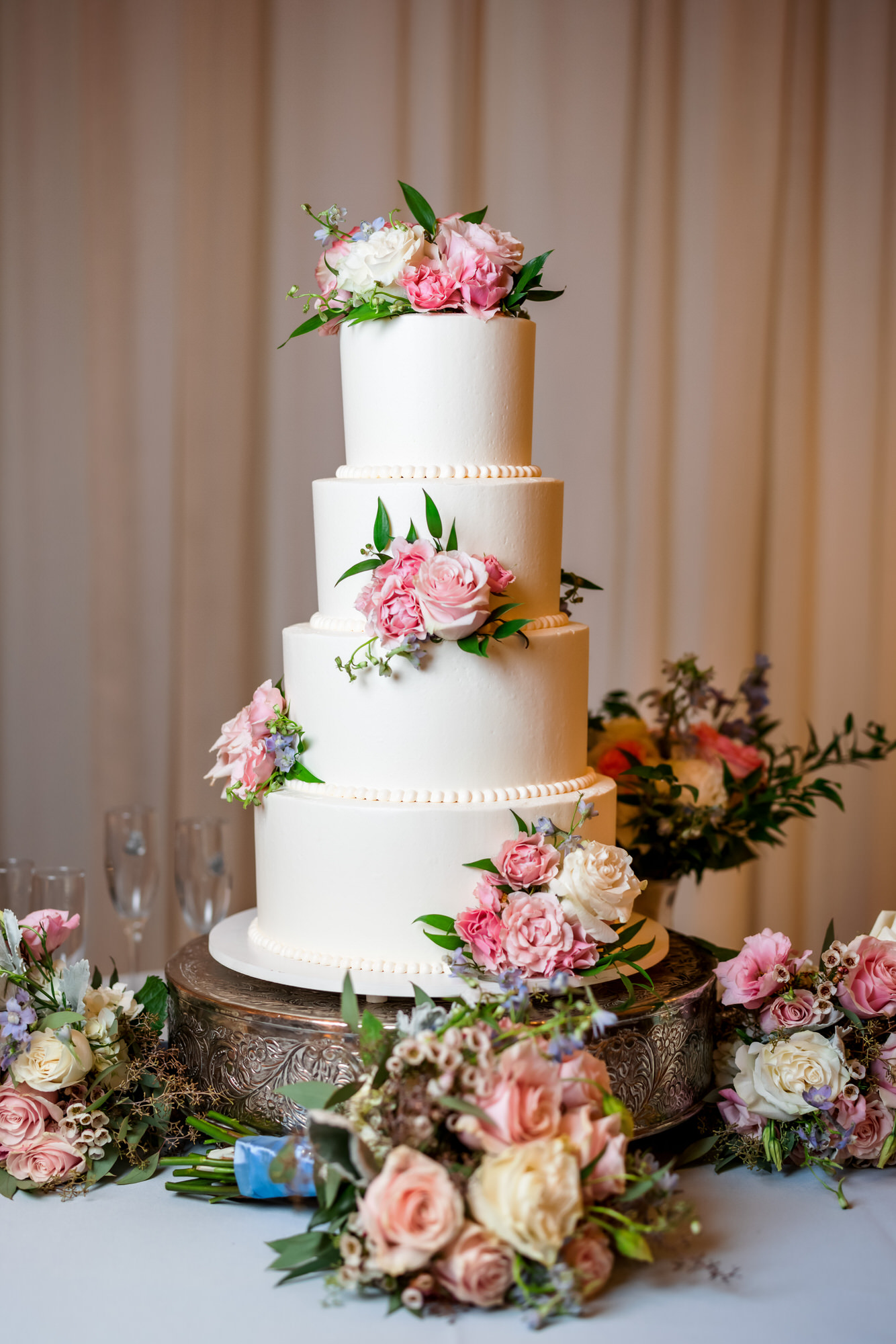 four tiered white wedding cake with pink and white florals throughout