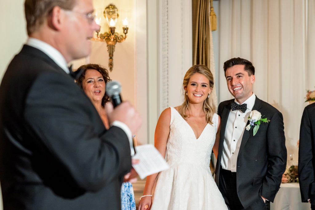 wedding couple hugging while father's bride gives toast 
