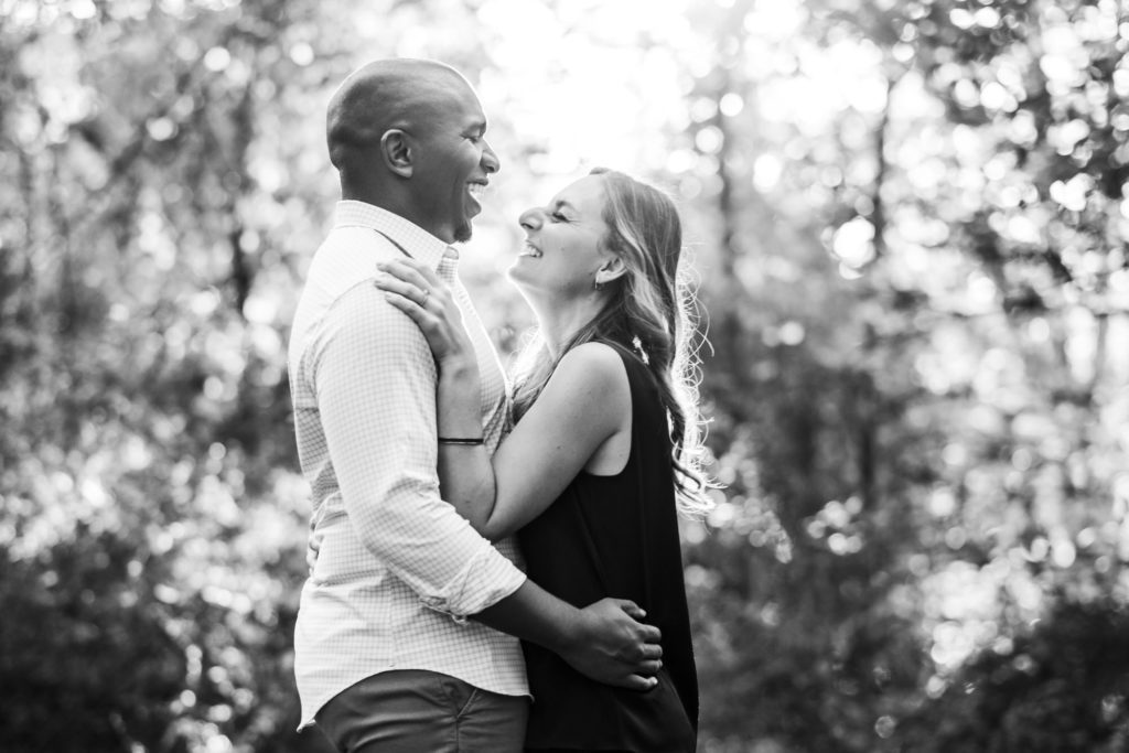 black and white image of newly engaged couple laughing together