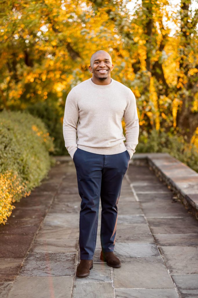 man wearing cream sweater and navy pants during outdoor engagement session