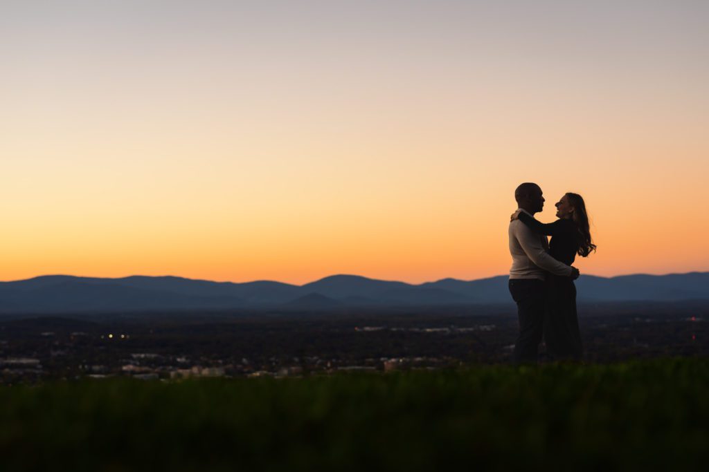 newly engaged couple holding one another during sunset engagement pictures