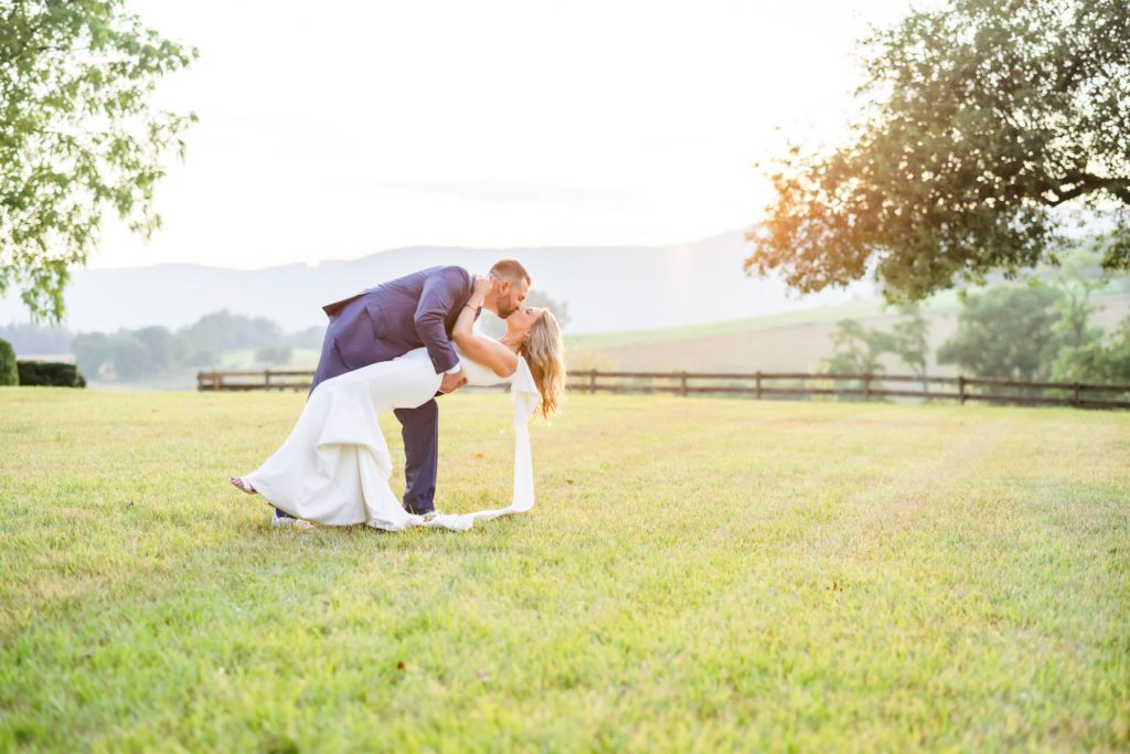 bride and groom kissing in field after summer charlottesville elopement