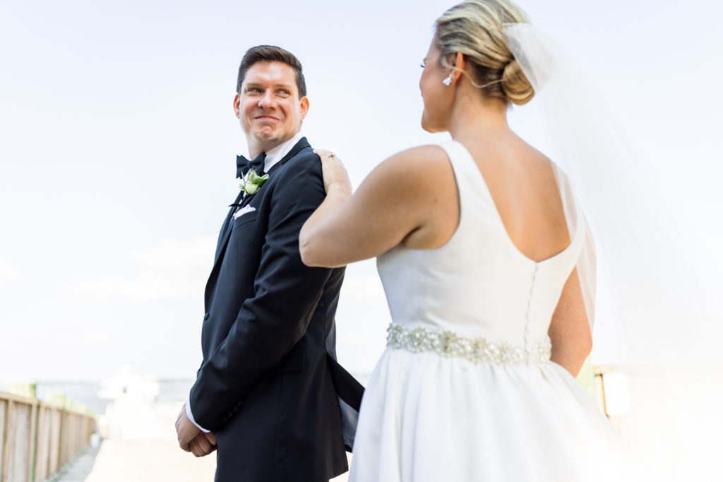 bride tapping groom's shoulder during first look at black tie eastern shore wedding
