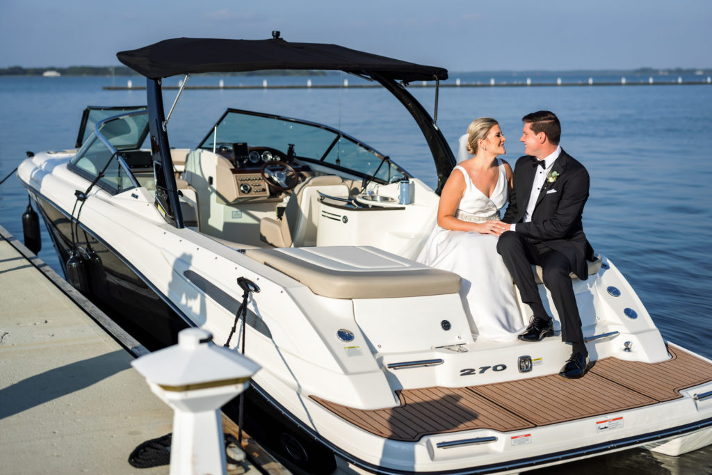 bride and groom sitting on boat during bridal portraits