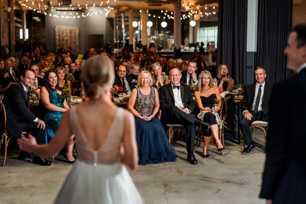 bride standing in front of guests during wedding reception