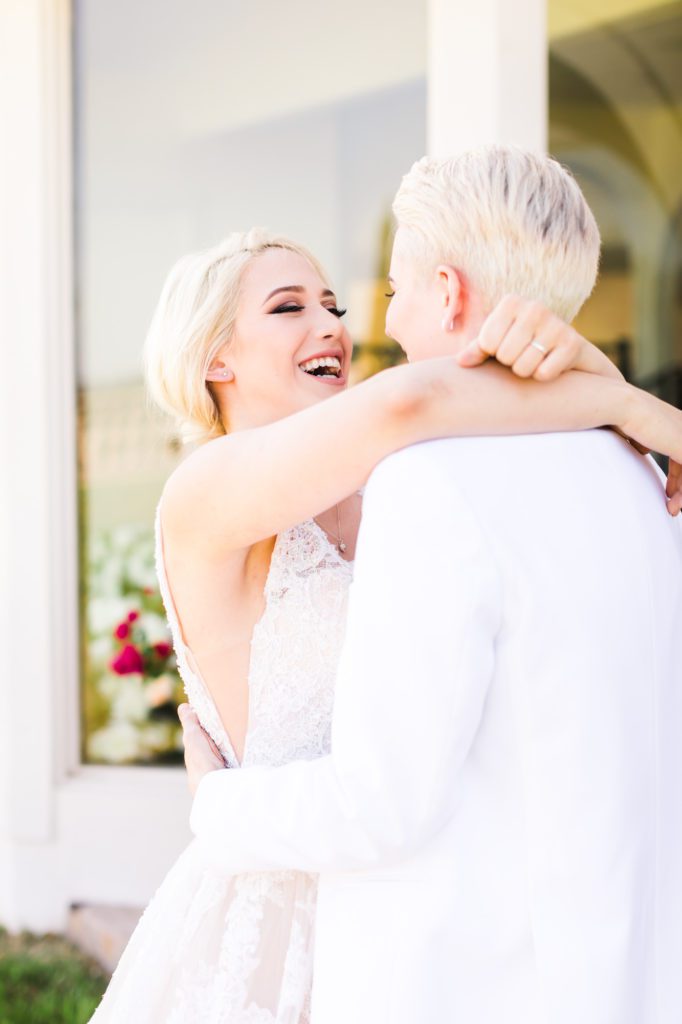 couple laughing and embracing wearing all white on wedding day