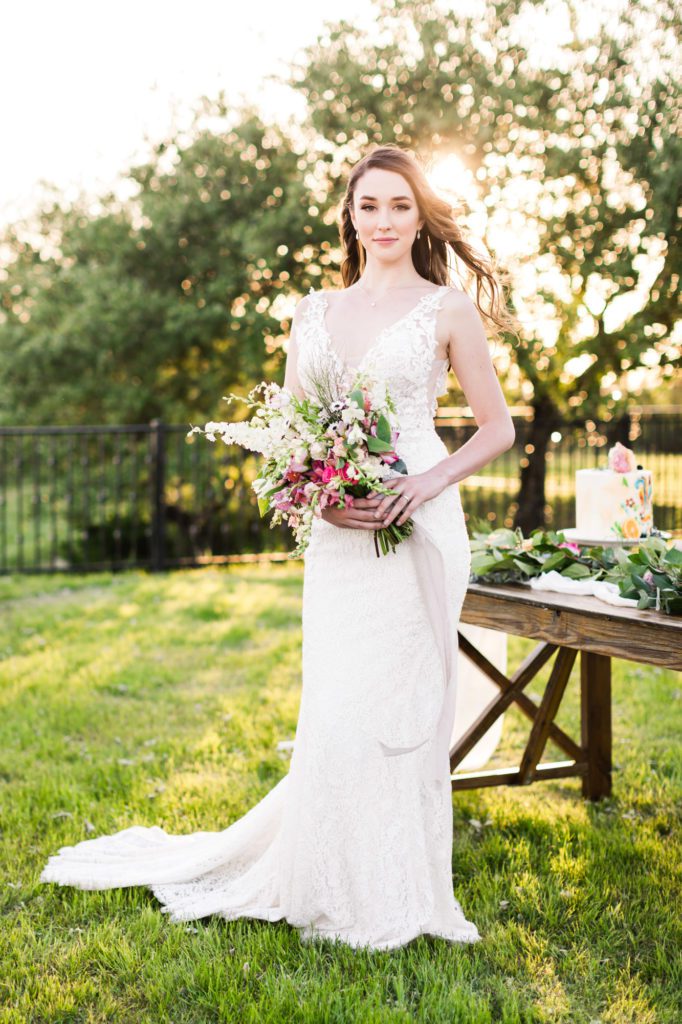 woman wearing simple lace wedding gown holding colorful bouquet
