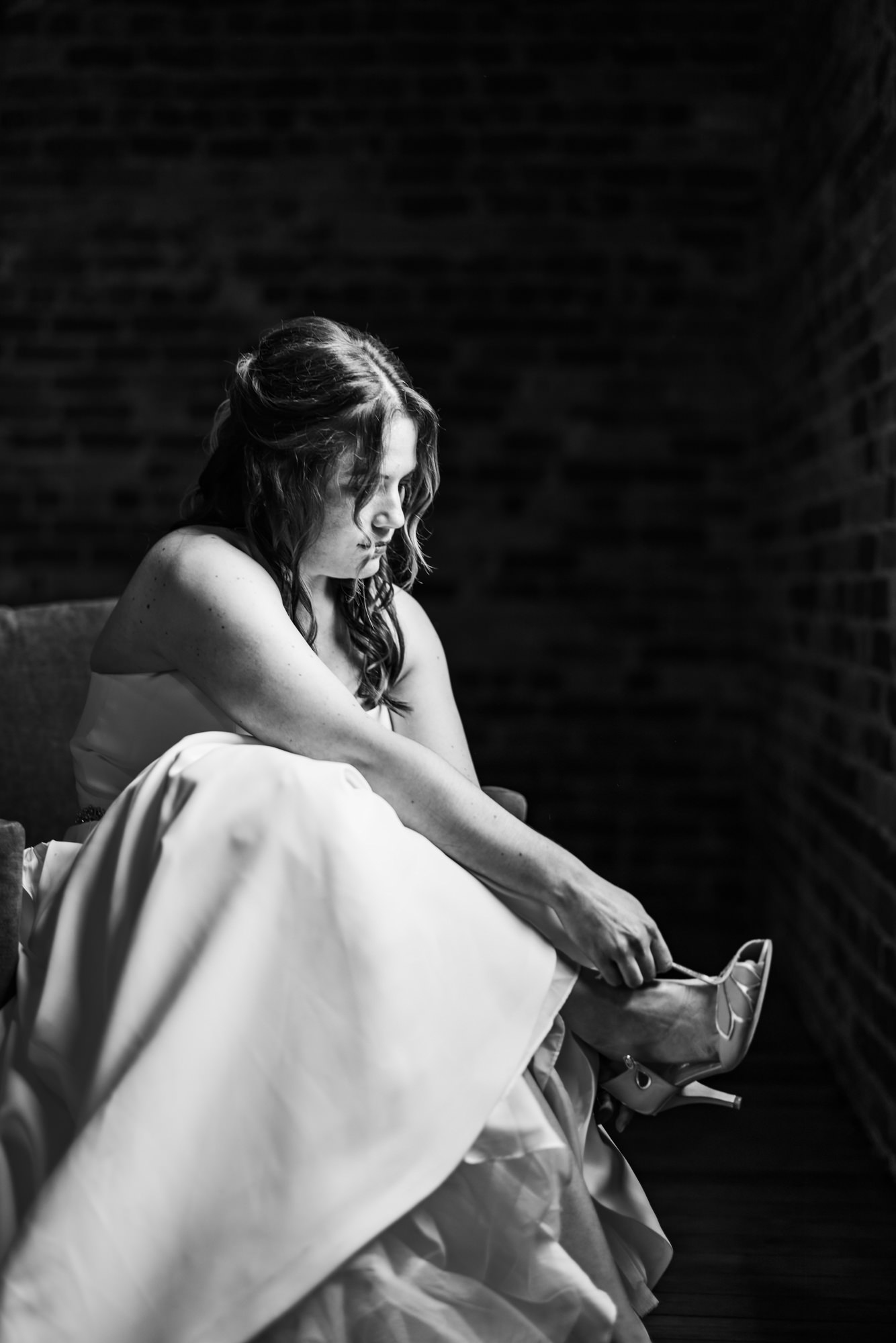 bride putting shoes on in white and black portrait