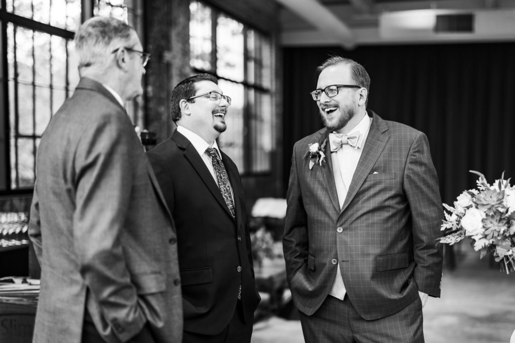 groom laughing with friends before intimate fall wool factory wedding