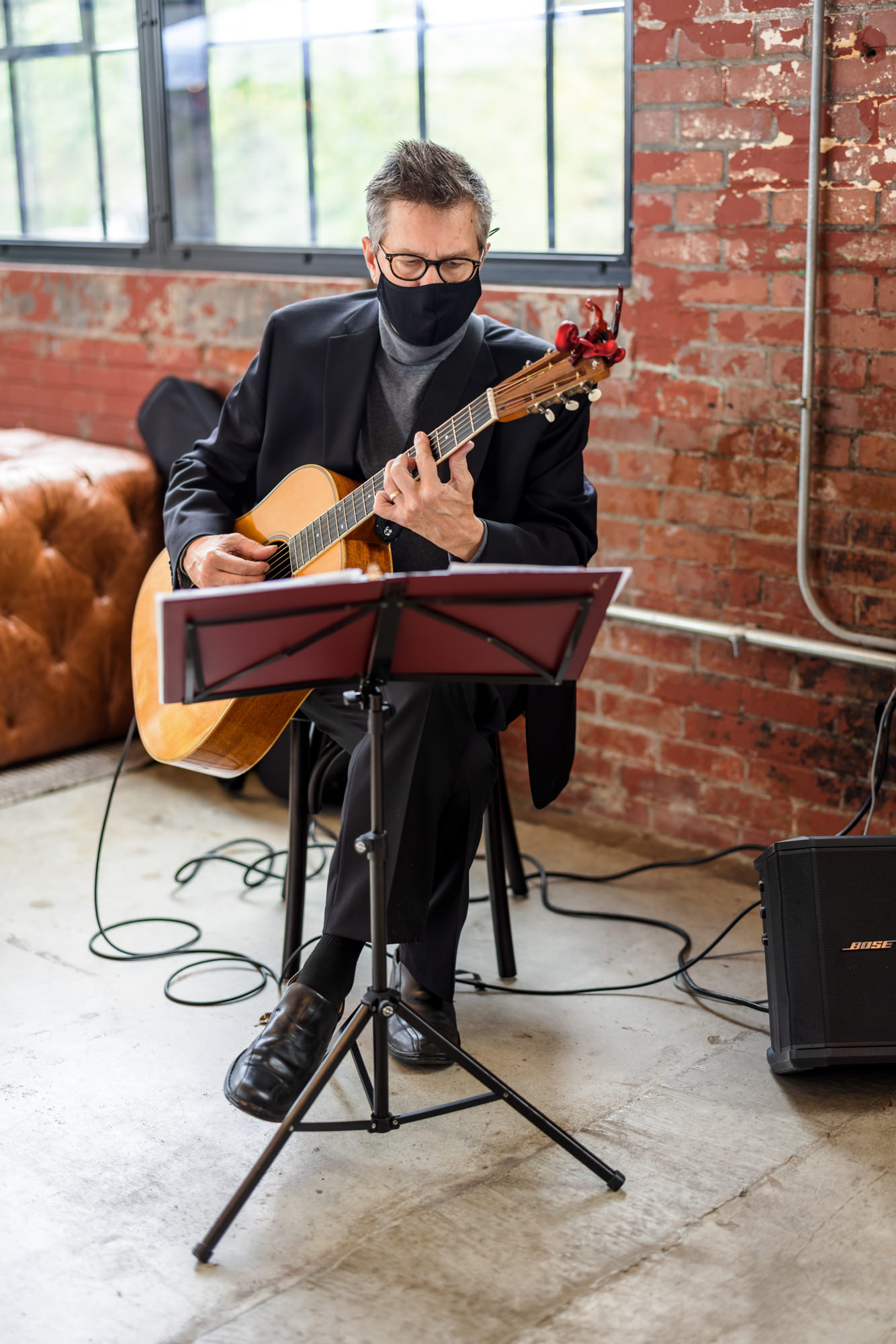 musician wearing mask playing guitar at intimate fall wool factory wedding