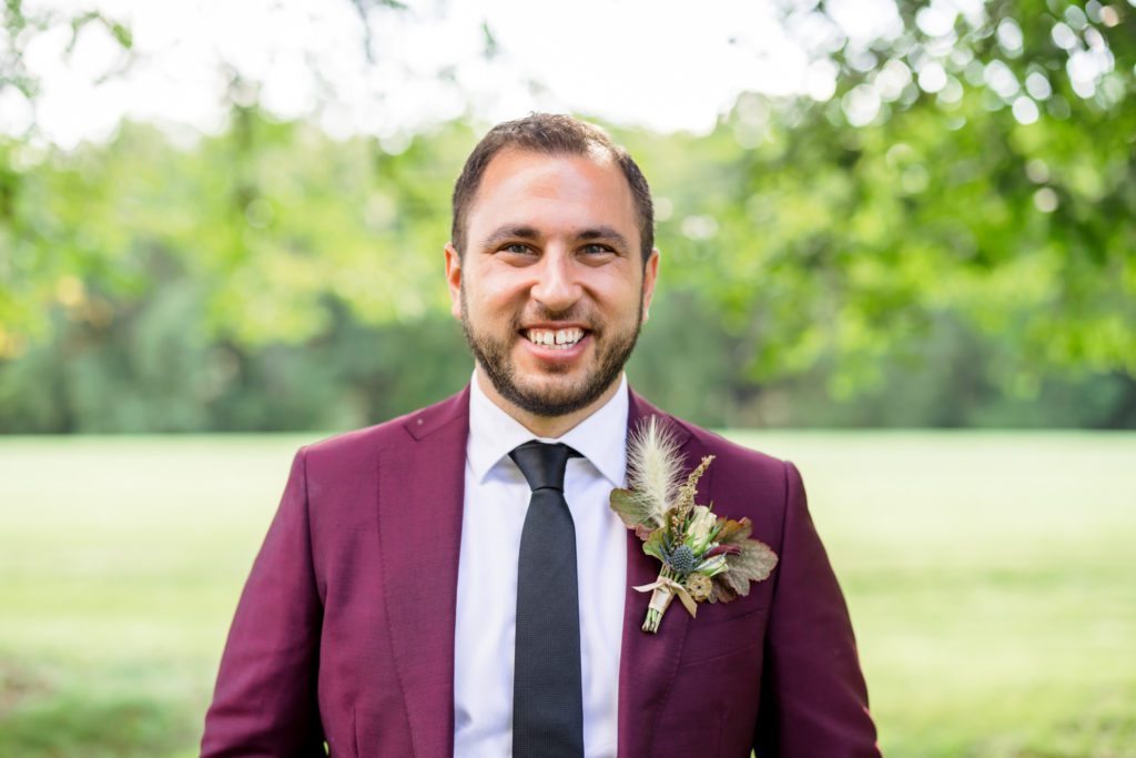 groom wearing burgundy suit with boho chic boutonnière 