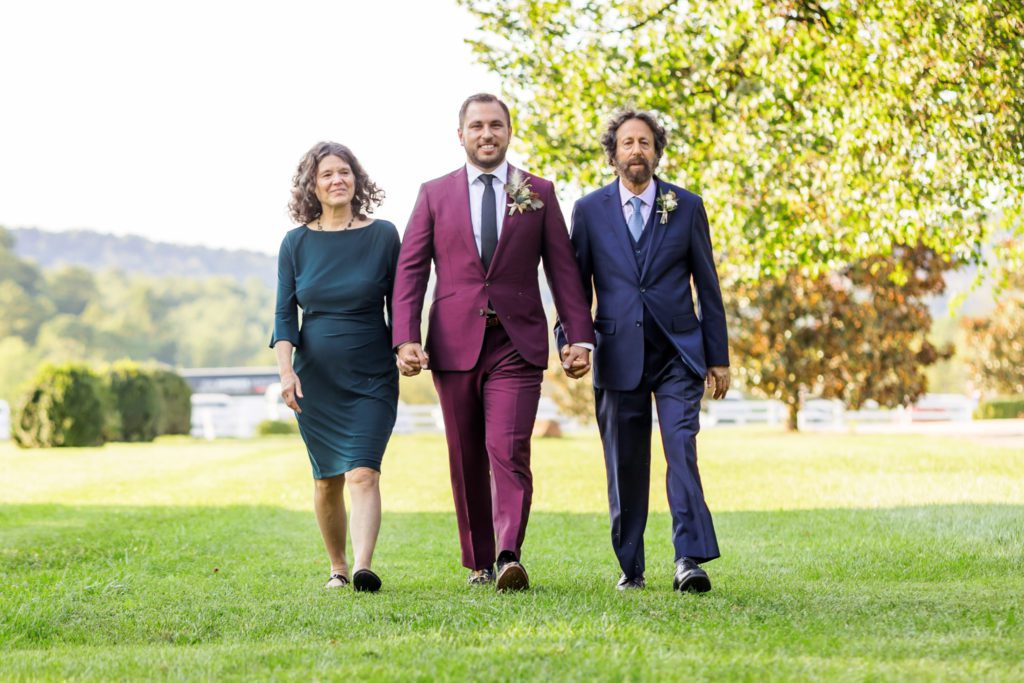 groom walking down aisle with parents