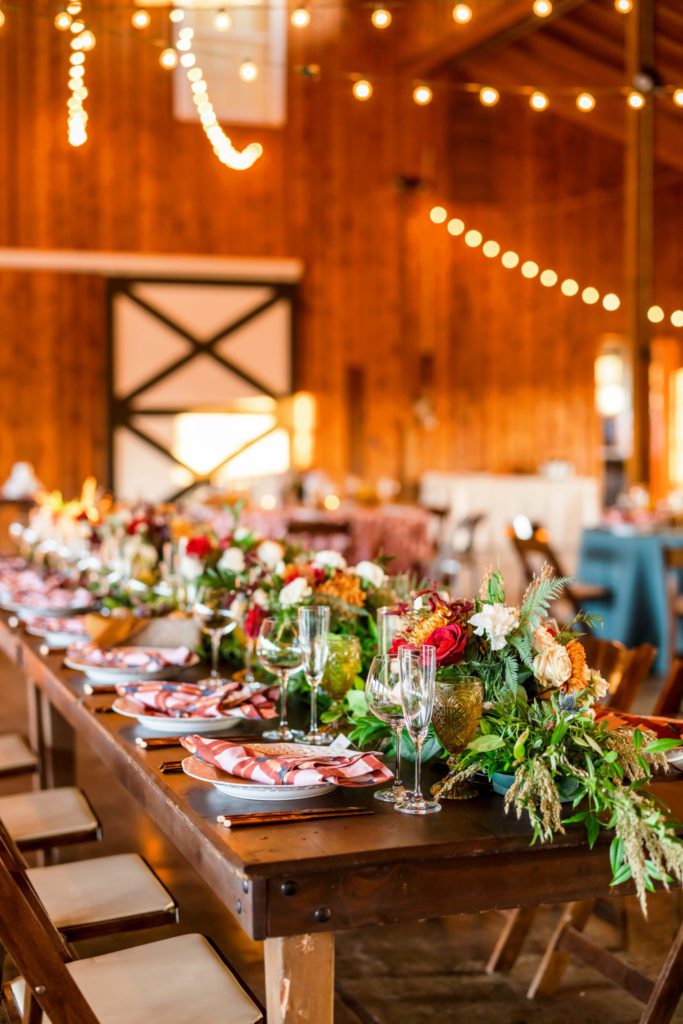 indoor rustic fall tablescape with greenery and warm lighting