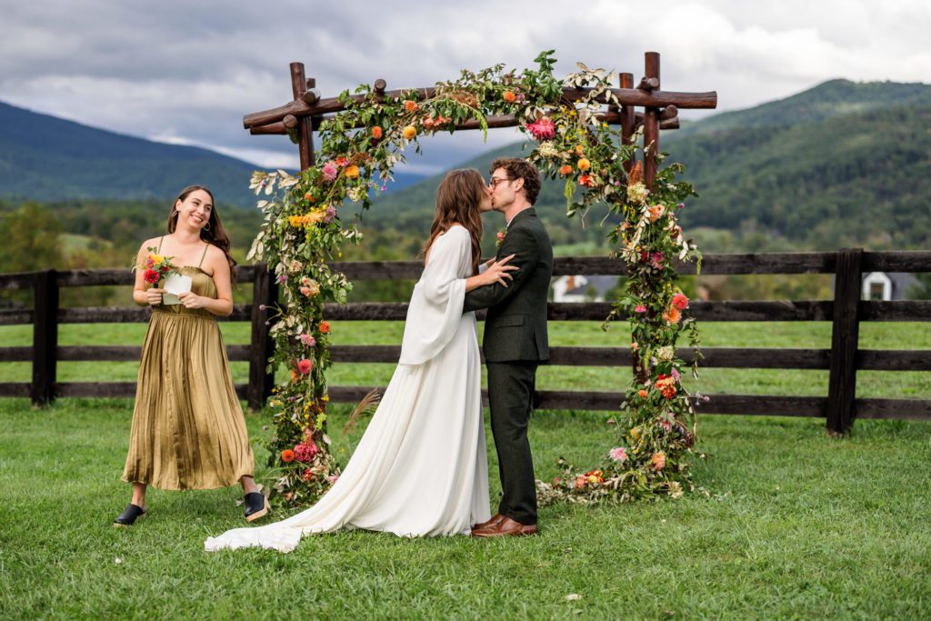 bride and groom kissing at colorful fall boho wedding ceremony