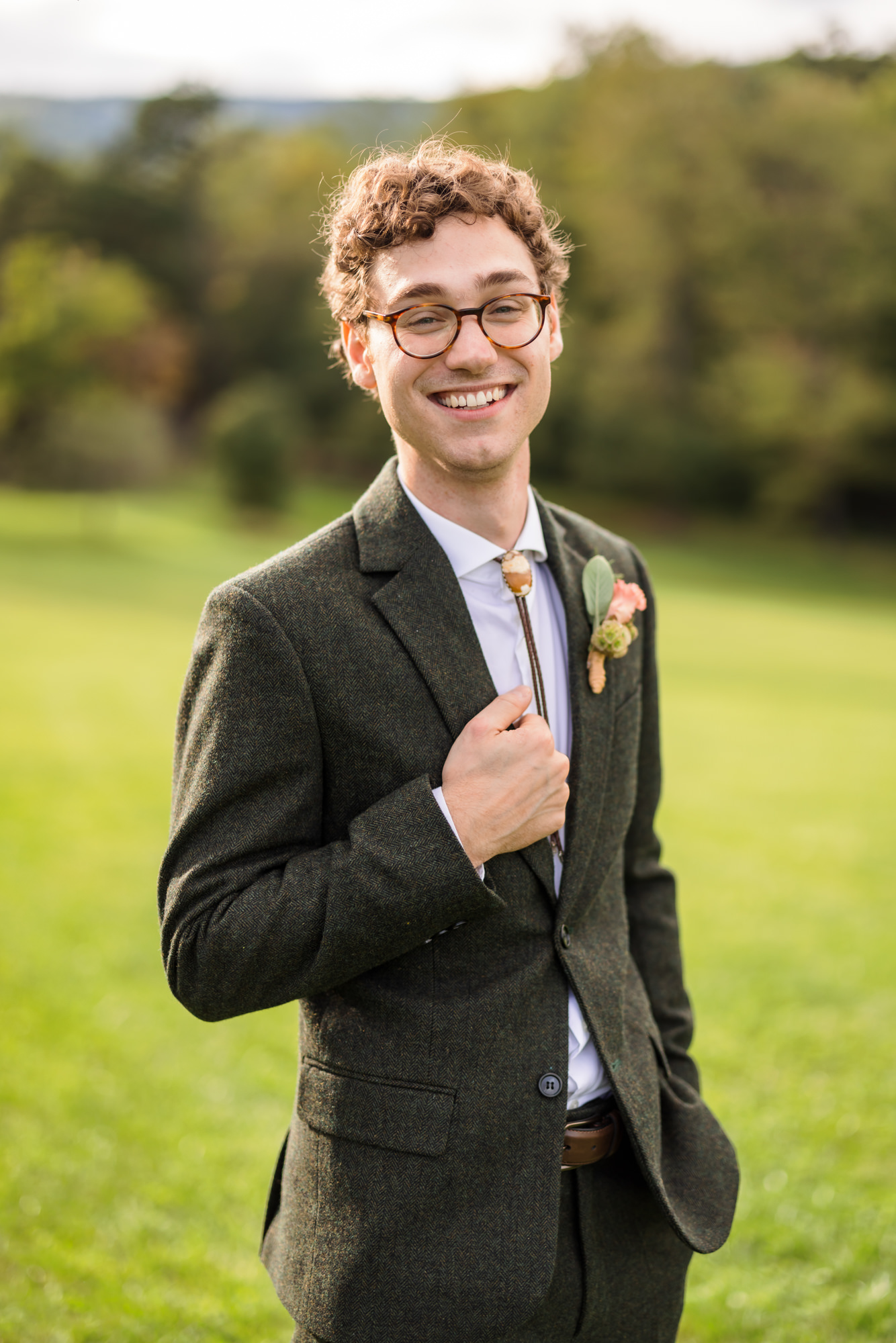 groom wearing olive coat holding lapel 