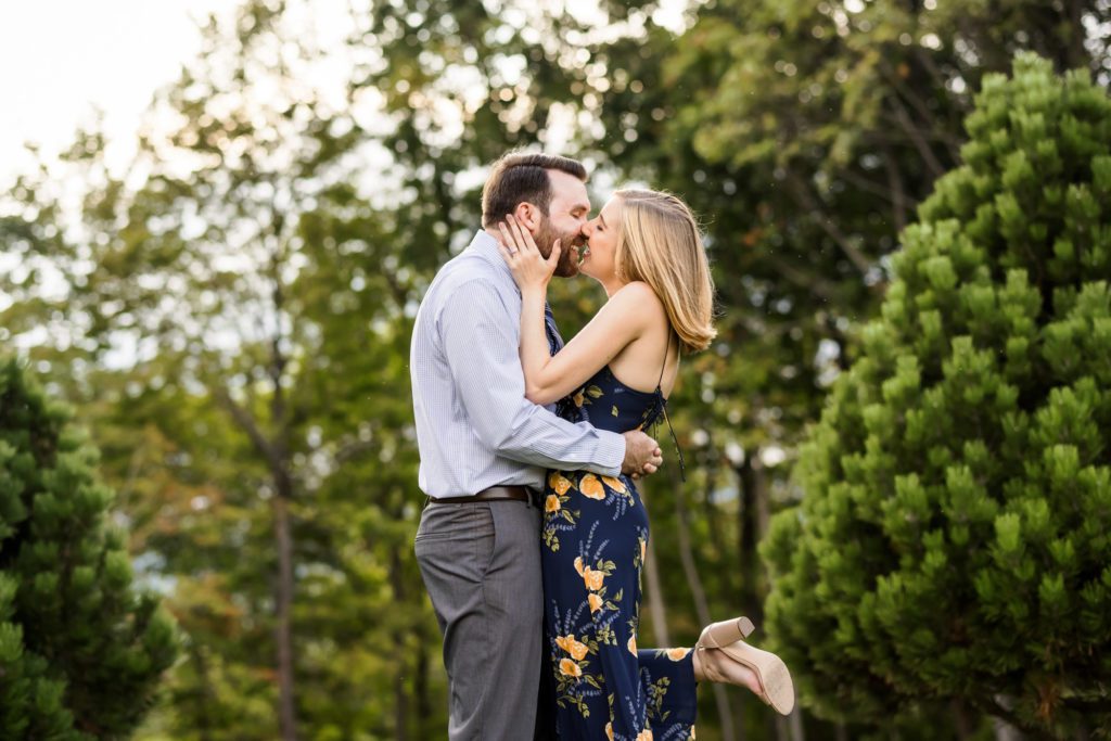 man and woman kissing during lexington engagement session while woman pops foot during kiss
