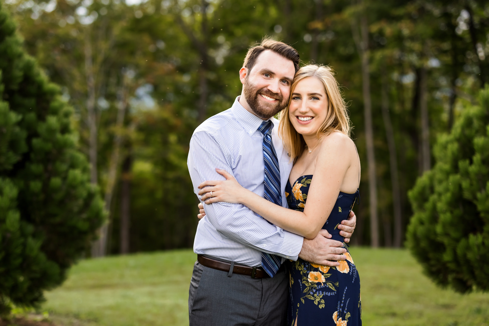 woman wearing navy floral dress and man wearing button down and tie during outdoor engagement session