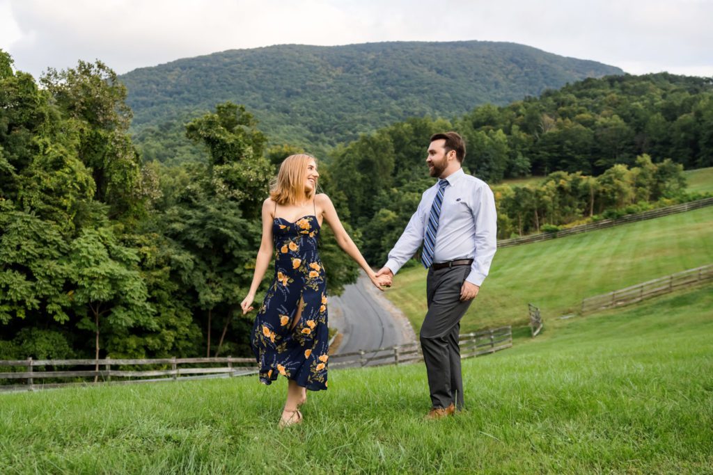 engaged couple holding hands walking with blue ridge mountains in background