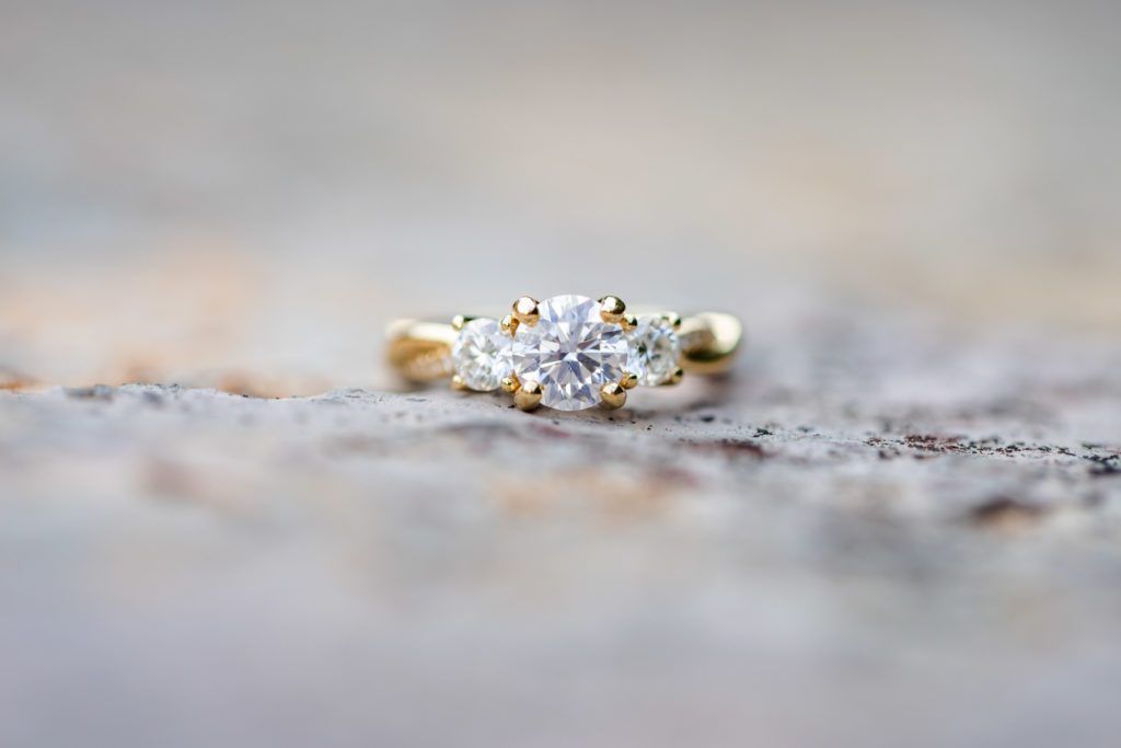 close up of gold engagement ring with 3 diamonds