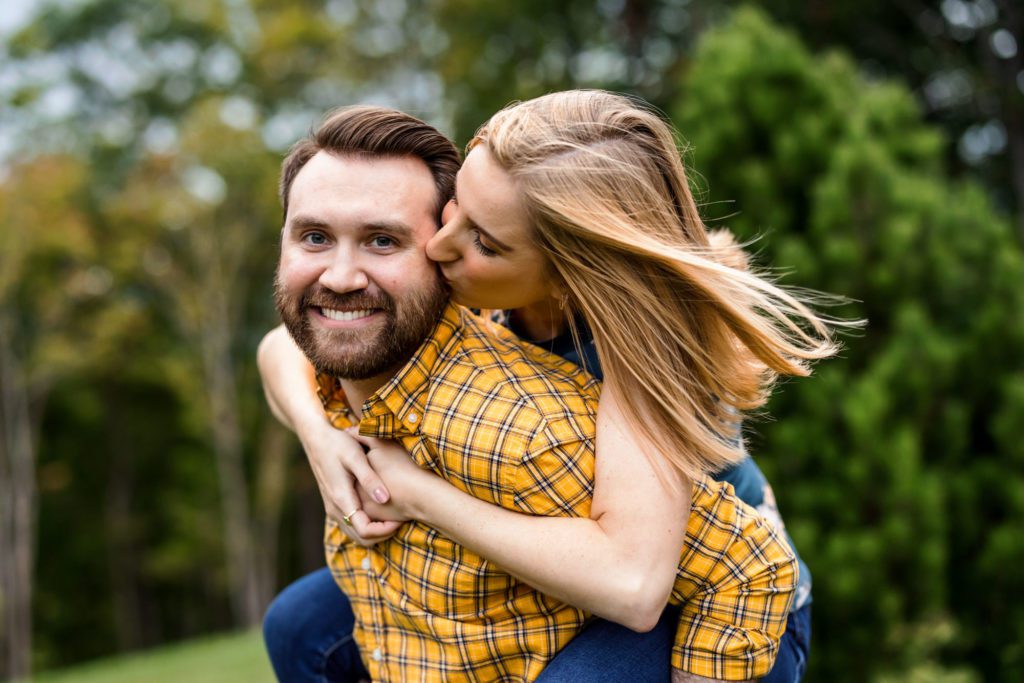 woman on man's back kissing his cheek during lexington engagement session