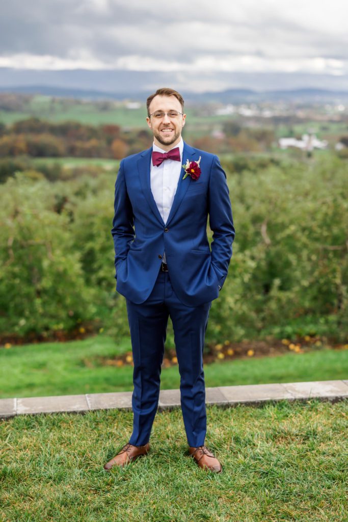 groom wearing navy suit with hands in pockets