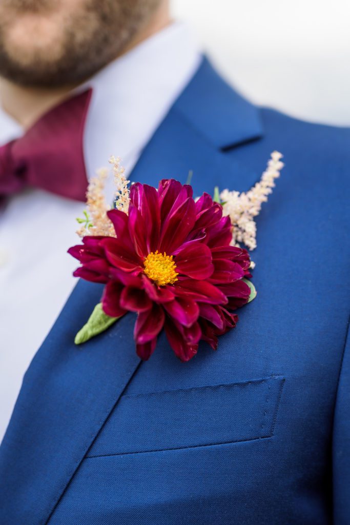 close up of groom's boutonniere burgundy dasiy