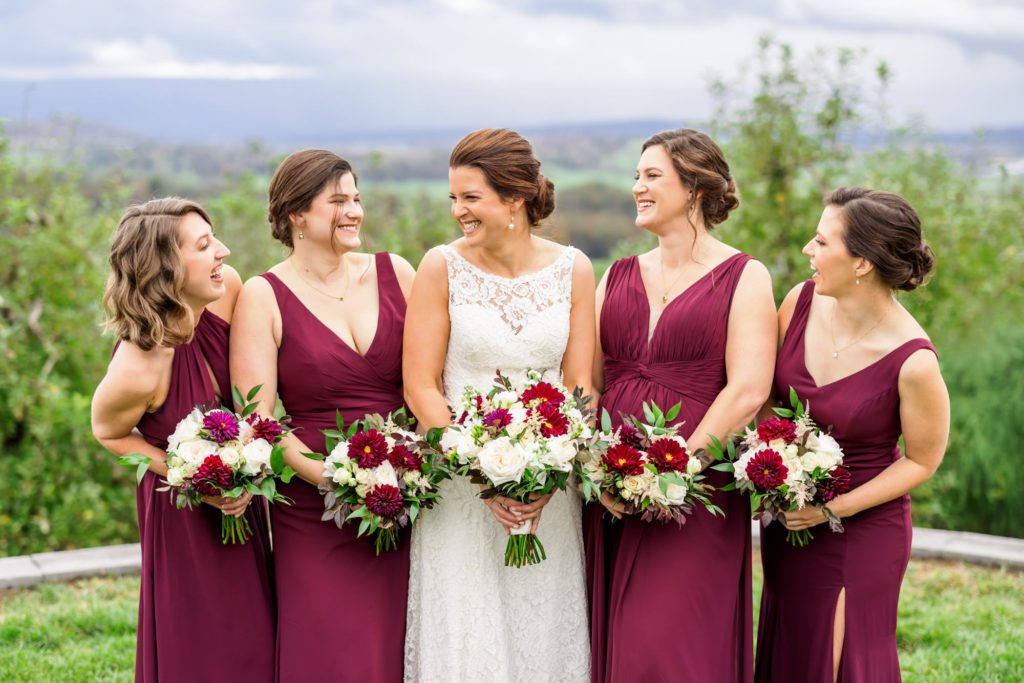 bride smiling and laughing with bridesmaids wearing burgundy dresses