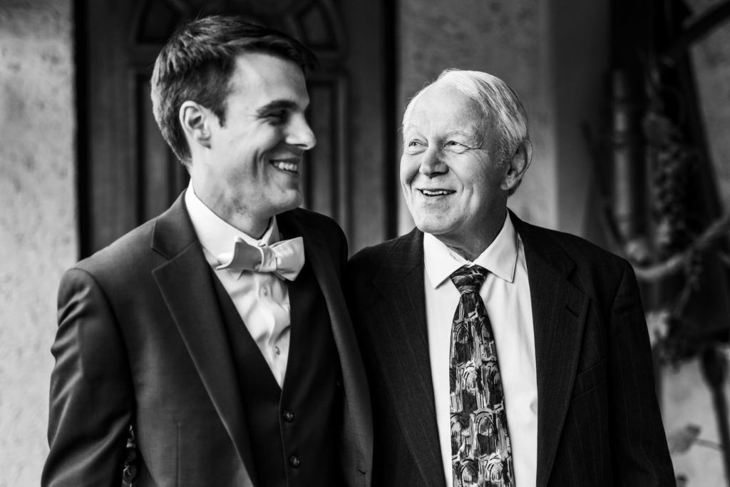 groom laughing with family in black and white portraits
