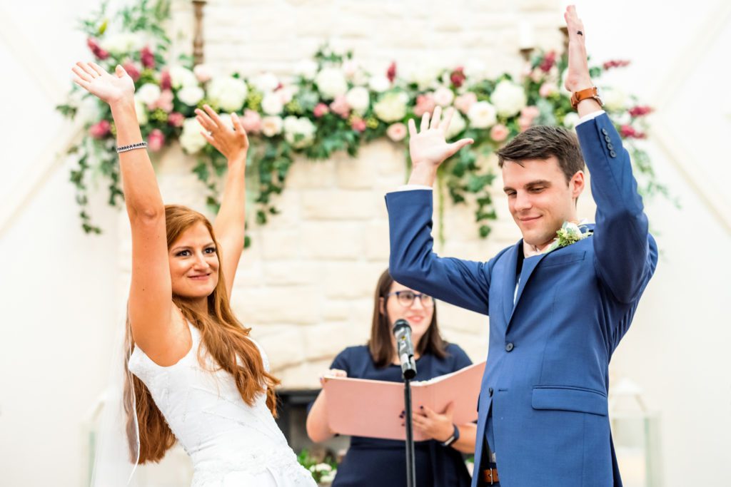 wedding couple raising arms celebrating during summer wedding ceremony