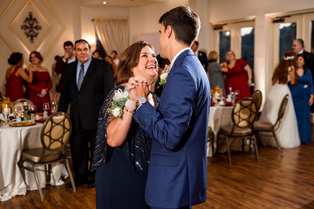 groom wearing navy suit dancing with mother wearing navy dress and rhinestone covered shawl