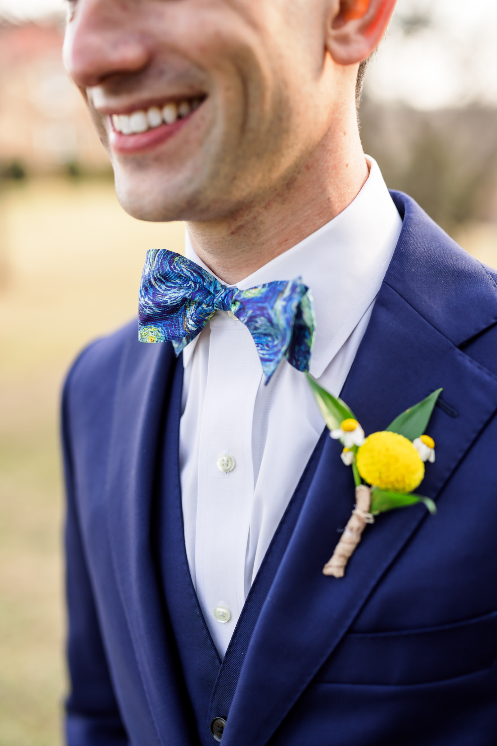 close up of groom's bow tie with starry night fabric and yellow boutonniere