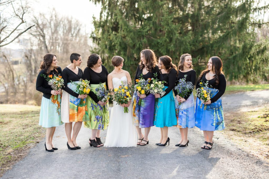 bride and bridesmaids during outdoor portraits all wearing colorful skirts with paintings of Van Gogh printed on them