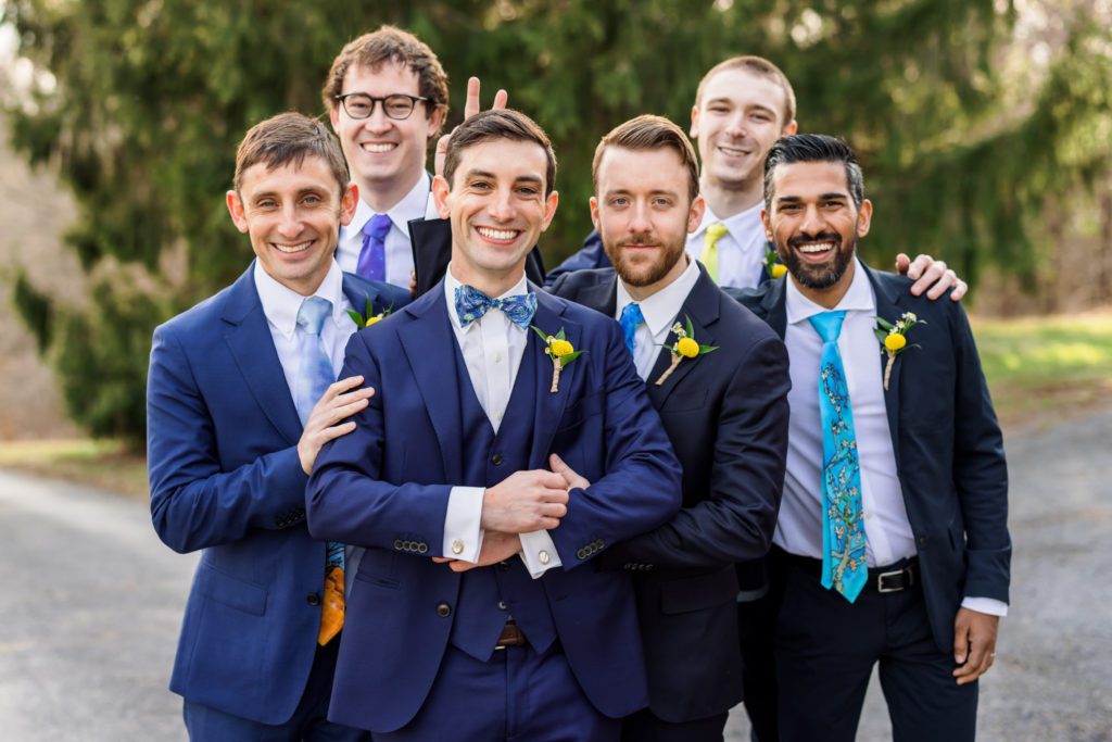 groom with groomsmen all wearing navy suits 