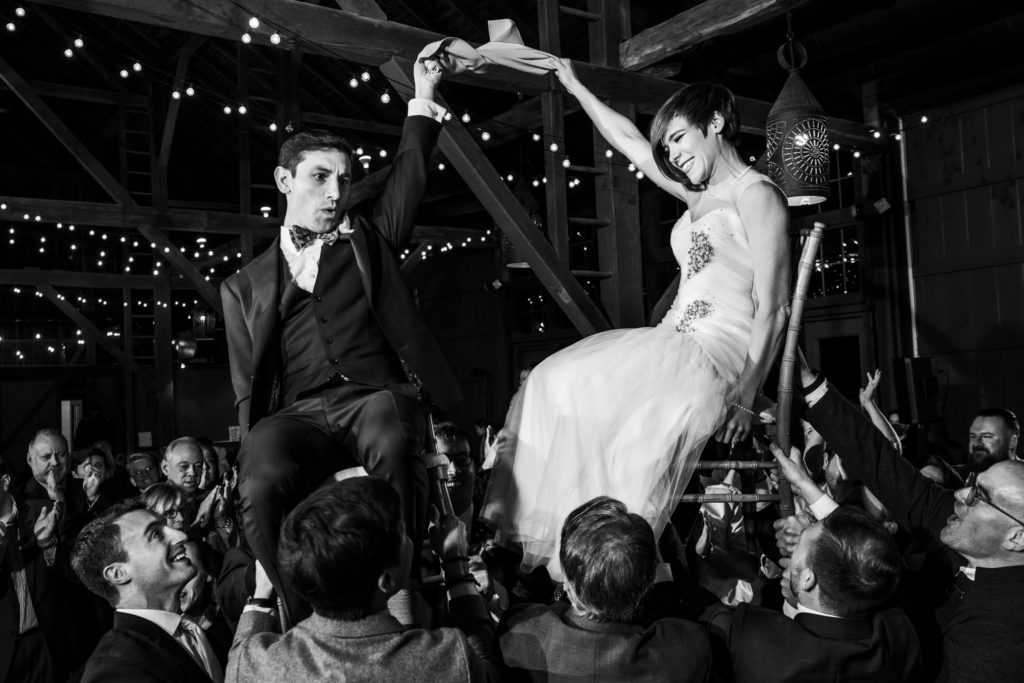 wedding couple lifted up on chairs celebrating at evening reception