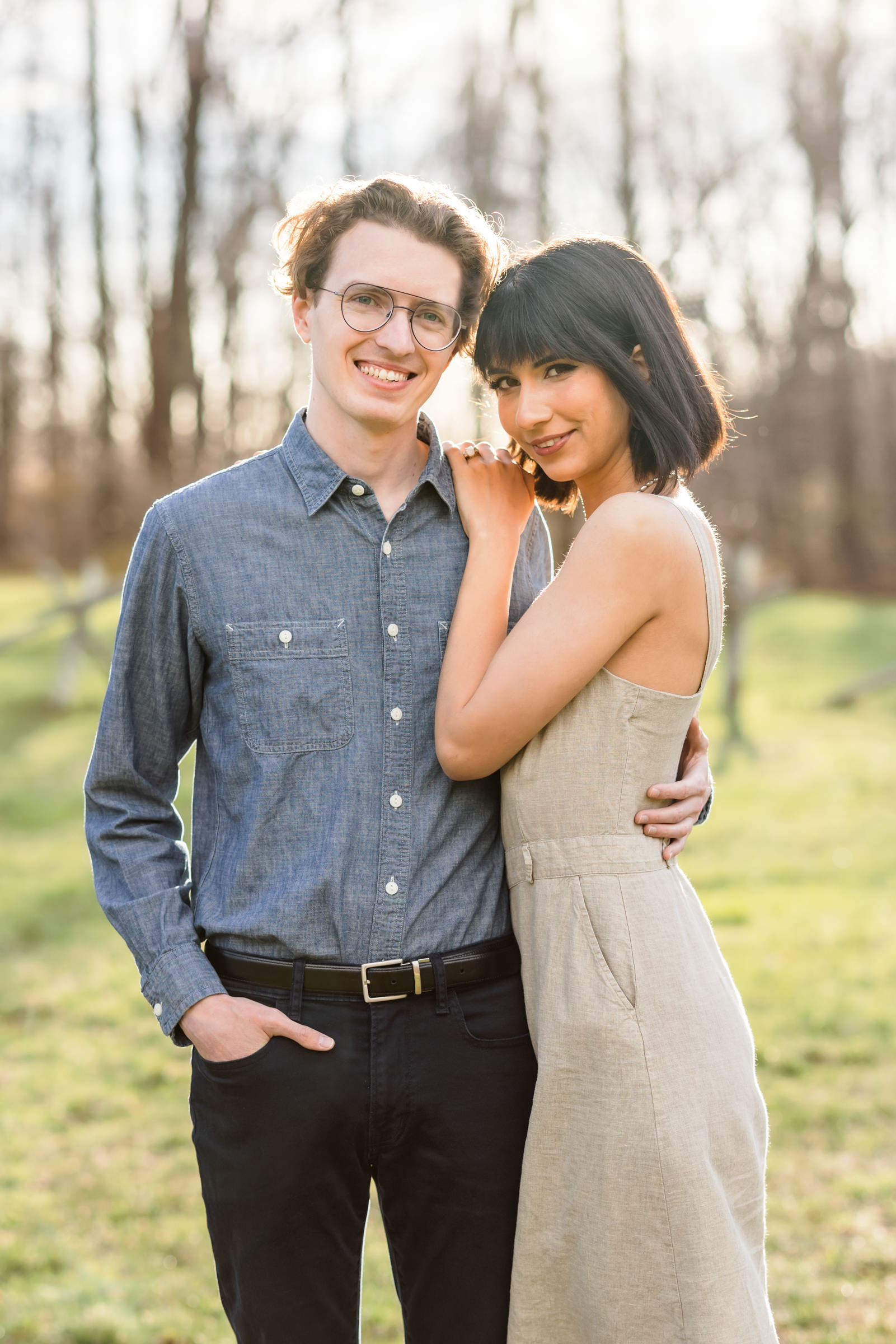 couple hugging during spring ravens roost engagement session wearing button down shirt and nude linen dress