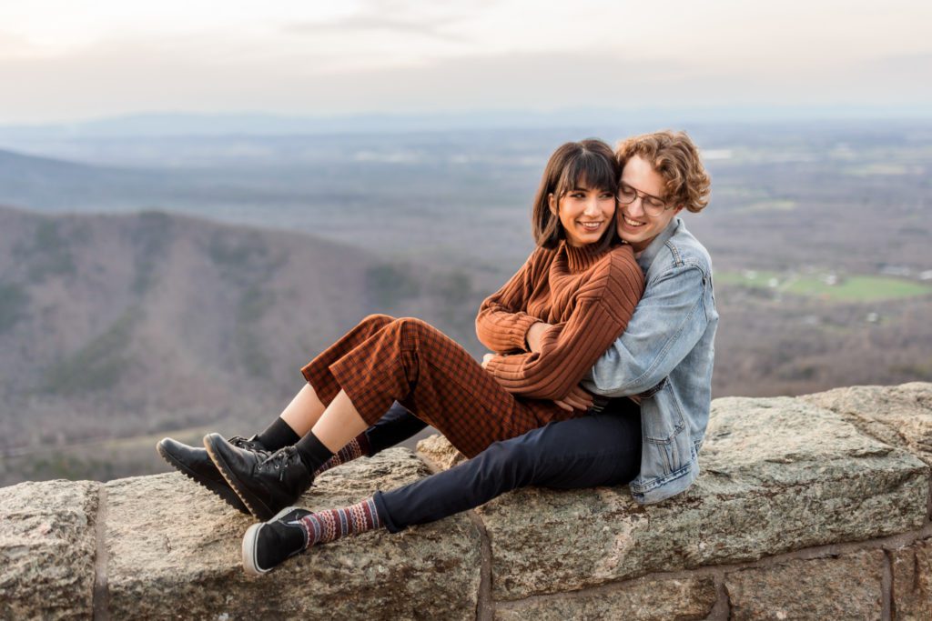 couple sitting on rock wall at ravens roost during couples portraits
