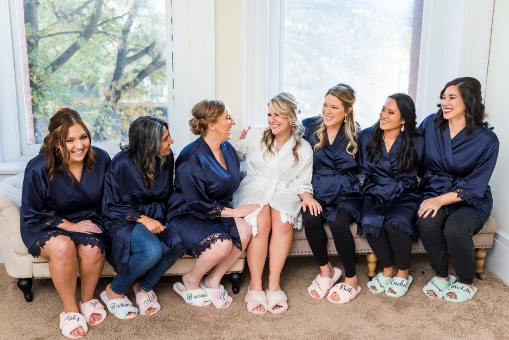 bride sitting with bridesmaids wearing matching robes 