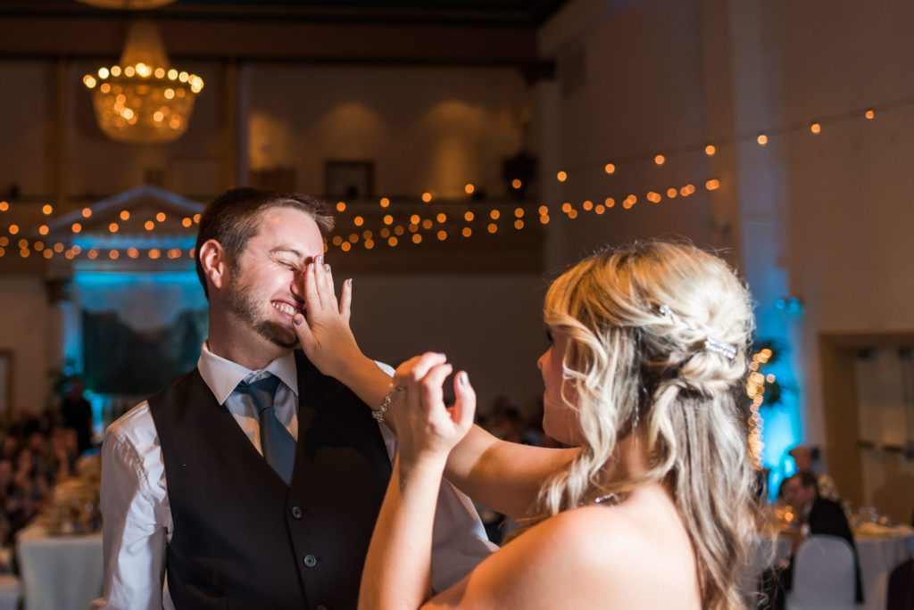 bride shoving cake in groom's face during cake cutting 